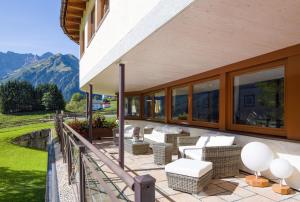 a patio with couches and chairs on a balcony with mountains at Hotel Leitner in Mittelberg