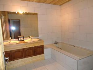 a bathroom with two sinks and a tub and a mirror at Odalys Chalet Erika in Les Deux Alpes