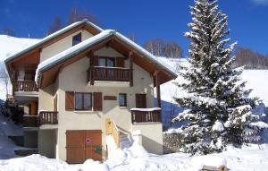 a house in the snow next to a christmas tree at Odalys Chalet Erika in Les Deux Alpes