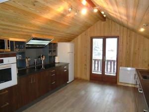 a large kitchen with wooden walls and wooden floors at Odalys Chalet Erika in Les Deux Alpes