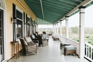 a porch with chairs and tables and a green roof at Chebeague Island Inn in Royal Junction