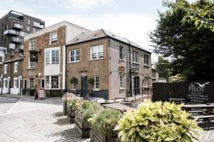 a brick building with potted plants in front of it at The Pilot Inn in London