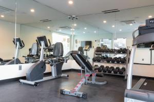 a gym with several treadmills and machines in a room at Hotel Xilo Glendale in Glendale