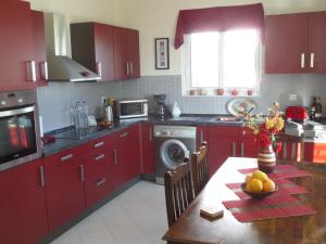 アルハンゲロスにあるVilla Tsampikaのキッチン(赤いキャビネット、フルーツの盛り合わせ付きテーブル付)