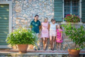 una familia parada frente a una casa de piedra en Antica Corte, en Soave