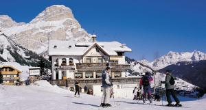 un grupo de personas esquiando frente a un lodge de esquí en Hotel Luianta, en Colfosco