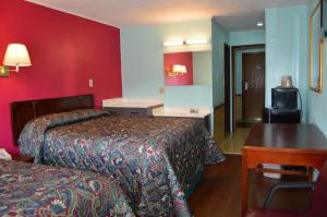 Habitación de hotel con 2 camas y escritorio en Budget Inn Richlands Claypool Hill, en Tazewell
