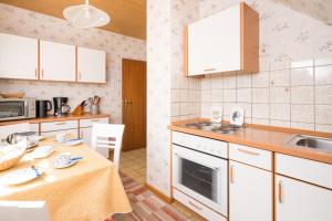 eine Küche mit weißen Schränken, einem Tisch und einem Waschbecken in der Unterkunft Gästehaus Ollech in Tating