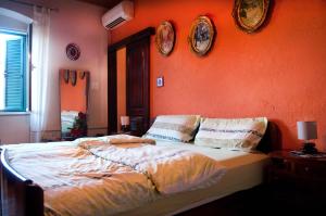 um quarto com uma parede laranja e uma cama com almofadas em Buga And Tuga Rooms em Split