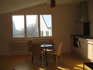 eine Küche mit einem Tisch und Stühlen sowie einem Fenster in der Unterkunft Appartement Les Iris in Bevaix