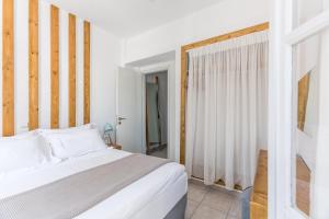 a bedroom with a white bed and a window at Fanouris Condo - Adults Only in Kamari