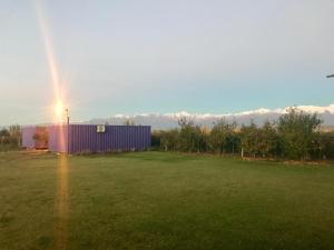 un arco iris en el cielo sobre un campo con un edificio en KooColand- XUMUC en Tupungato