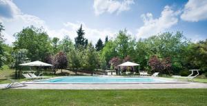 a swimming pool with chairs and umbrellas in a yard at I Pianelli in Murlo