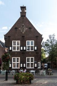 a large red brick building with white windows and tables at Vesting Hotel Naarden in Naarden