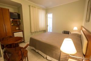 a bedroom with a bed and a table and a lamp at Hotel Ipanema de Sorocaba in Sorocaba