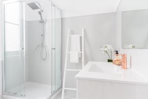 uma casa de banho branca com um chuveiro e um lavatório. em City Lofts Lisbon - Guesthouse em Lisboa