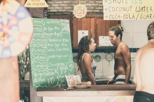 a man and a woman standing in a kitchen at Lagarto Na Banana Hostel in Pipa