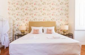 um quarto com uma grande cama branca com flores cor-de-rosa em City Lofts Lisbon - Guesthouse em Lisboa