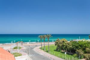 een straat met palmbomen en de oceaan op de achtergrond bij Amigo Hotel On The Beach in Nahariyya