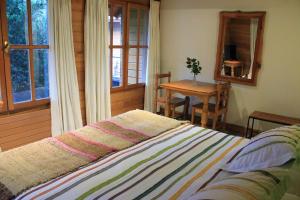 1 dormitorio con cama, mesa y ventana en Hotel Malalhue, en Pucón