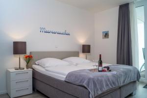 een slaapkamer met een groot bed en een fles wijn bij Südkap F-03 in Pelzerhaken
