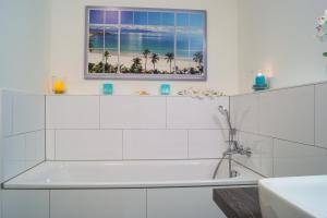 a white bathroom with a tub and a window at Südkap F-03 in Pelzerhaken +39 photos
