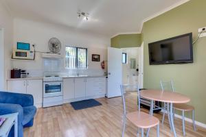 sala de estar con mesa y TV en la pared en Port Huon Cottages, en Port Huon