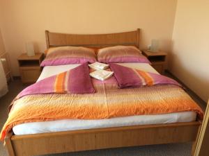 a bed with purple and orange blankets and pillows at Margitapartman in Bük