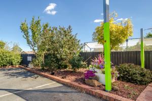 a parking lot with a green pole and flowers at Werribee Motel and Apartments in Werribee