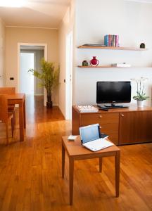 ein Wohnzimmer mit einem TV und einem Tisch mit einem Laptop in der Unterkunft Cosmo Residence in Vimercate