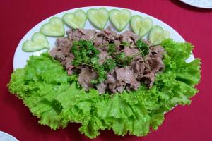 a plate of food with meat and lettuce and cucumbers at Dai Long Hotel in Da Nang
