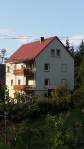 een groot wit huis met een rood dak bij Ferienwohnung Bergblick in Kleingießhübel