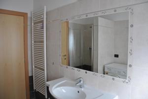 La salle de bains blanche est pourvue d'un lavabo et d'un miroir. dans l'établissement Casa Gabriella, à Fiera di Primiero