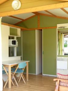 a kitchen with green walls and a table and chairs at Camping L´Amuravela in Cudillero