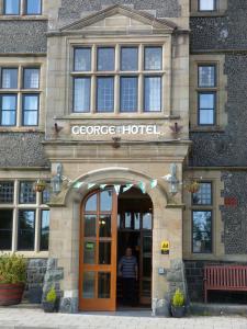 un hombre parado en la puerta de un edificio en George IV Hotel, en Criccieth