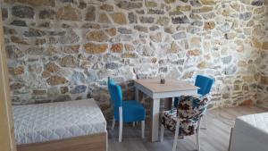 a table and chairs in a room with a stone wall at Rooms Ela Ela in Prekodolce