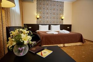 um quarto de hotel com uma cama e uma mesa com um vaso de flores em Kaluga Plaza em Kaluga
