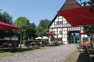 ein Gebäude mit Tischen, Stühlen und roten Sonnenschirmen in der Unterkunft Hotel Restaurant Hof Hueck in Bad Sassendorf