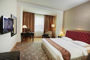 a hotel room with a large bed and a desk at Rocky Plaza Hotel Padang in Padang