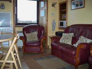 a living room with a couch and a chair and a table at Roadside Cottage in Sandwick