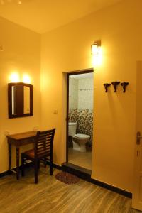 uma casa de banho com uma mesa, um WC e um espelho. em Janatha Homestay em Cochin