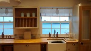 a kitchen with a sink and two windows at Jasmine Cottage in Llangollen