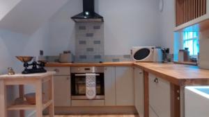 a kitchen with a wooden counter top with a microwave at Jasmine Cottage in Llangollen