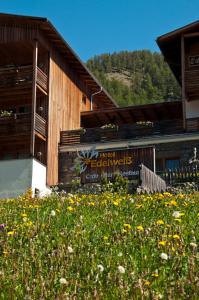 un bâtiment avec un champ de fleurs devant lui dans l'établissement Hotel Edelweiss, à Malles Venosta