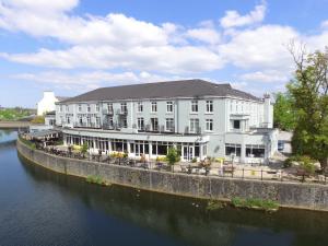 a large white building next to a body of water at Kilkenny River Court Hotel in Kilkenny