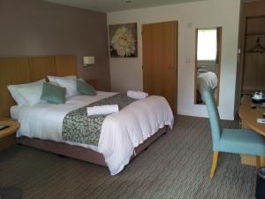una habitación de hotel con una cama grande y una silla azul en Deangate Motel, en Lydney