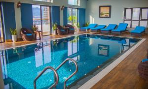 una piscina con sillas azules en una habitación de hotel en Eco Green Boutique Hotel Da Nang, en Da Nang