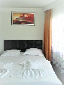 uma cama com lençóis brancos e uma foto na parede em Bereket traveler Hotel em Istambul
