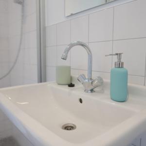 a bathroom sink with a blue soap dispenser on it at VierVaart Studio appartement in Groede