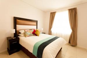 Un dormitorio con una cama grande y una ventana en Apartments @ 125 en Gaborone